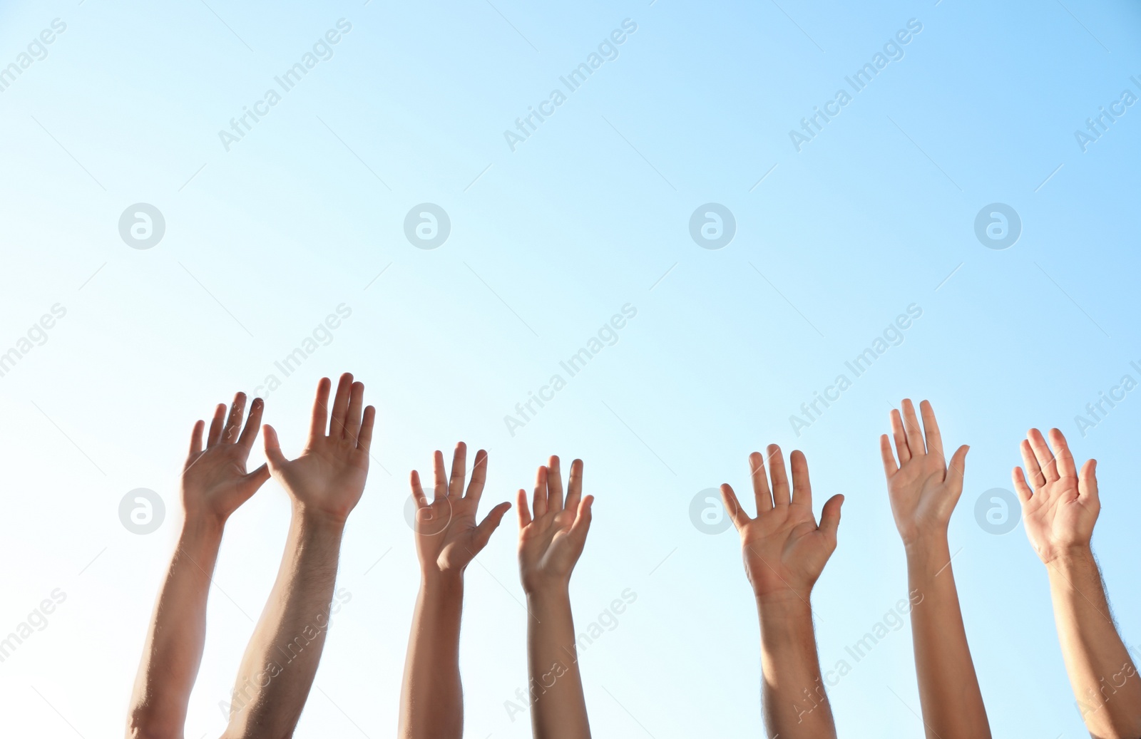 Photo of Group of volunteers raising hands outdoors, closeup