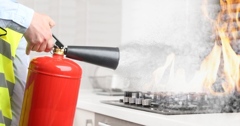 Image of Man putting out burning cooktop with fire extinguisher in kitchen, closeup. Banner design