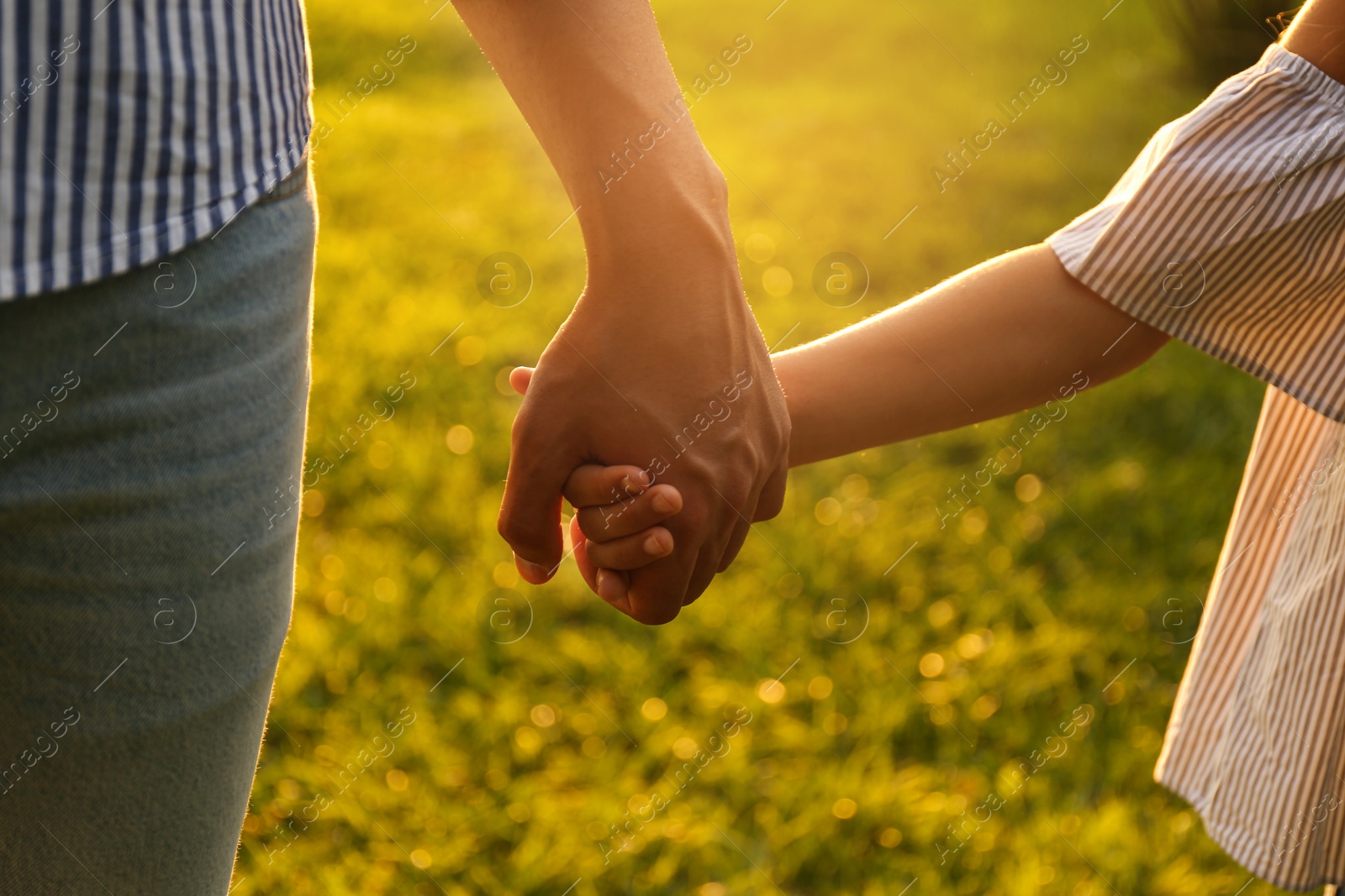 Photo of Little girl and her father holding hands in park, closeup. Happy family