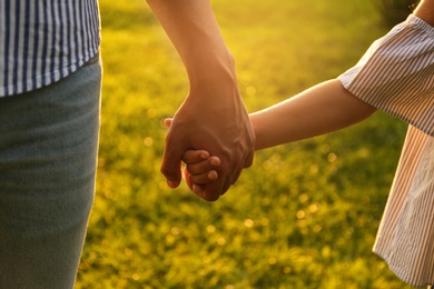 Little girl and her father holding hands in park, closeup. Happy family