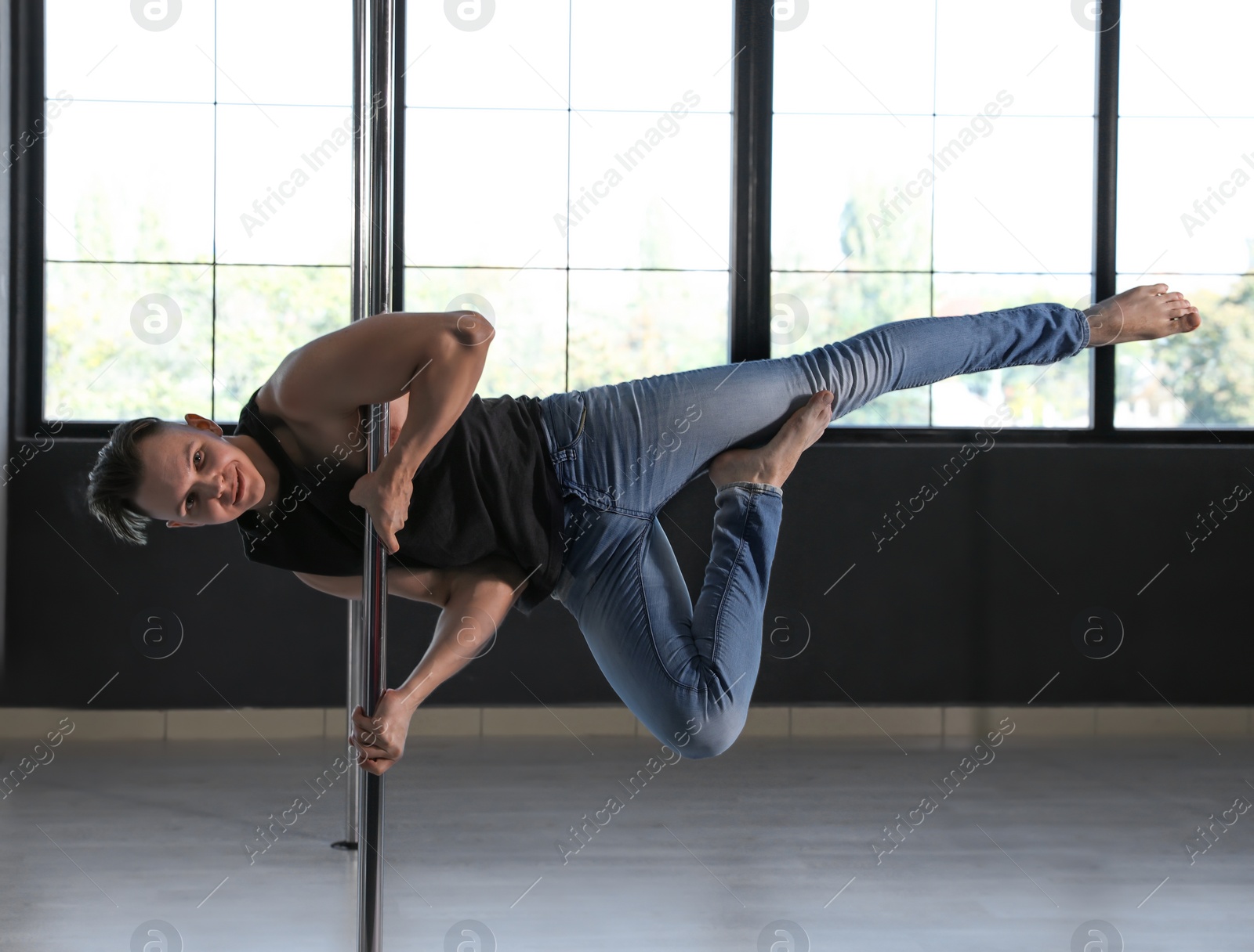 Photo of Attractive young man dancing in studio with poles