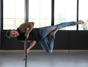 Photo of Attractive young man dancing in studio with poles