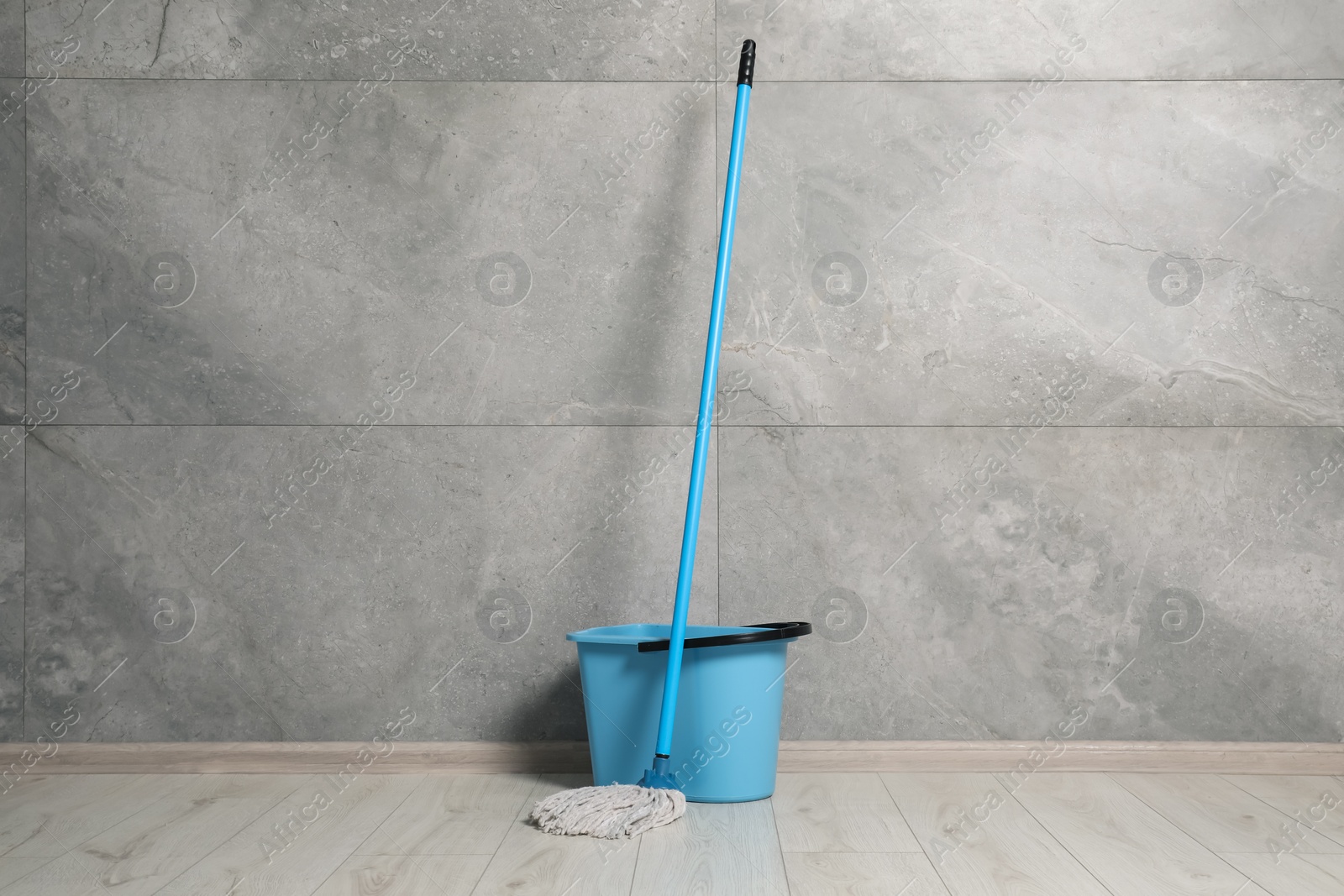 Photo of Mop and plastic bucket indoors. Cleaning floor