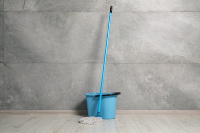 Photo of Mop and plastic bucket indoors. Cleaning floor