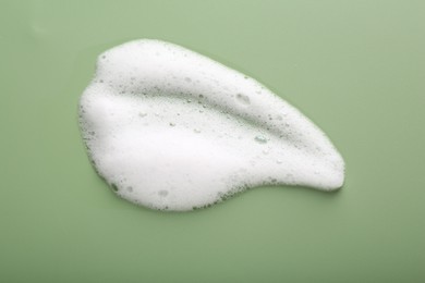 Sample of fluffy foam on green background, top view