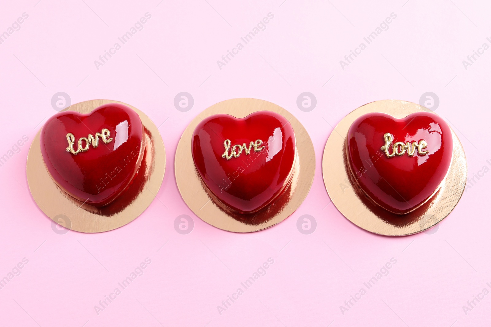 Photo of St. Valentine's Day. Delicious heart shaped cakes on light pink background, flat lay