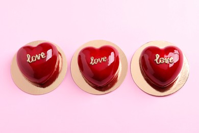 Photo of St. Valentine's Day. Delicious heart shaped cakes on light pink background, flat lay