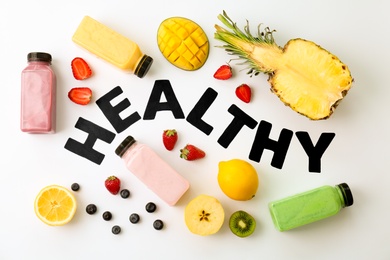 Photo of Flat lay composition with word HEALTHY, detox smoothies and ingredients on light background