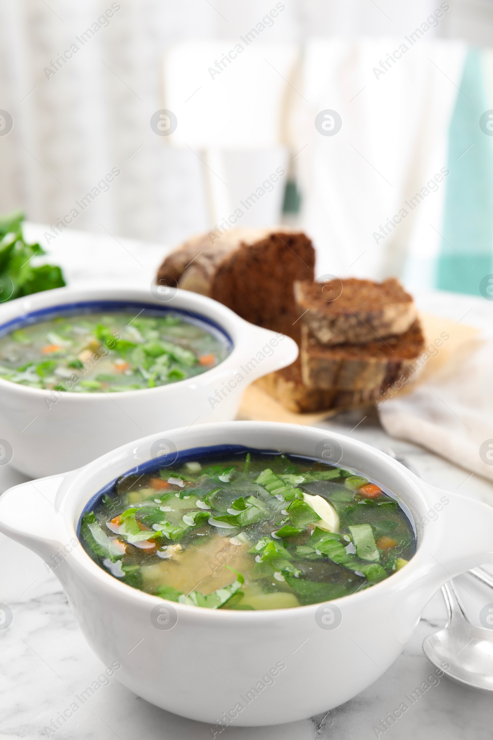 Photo of Delicious sorrel soup served on white marble table