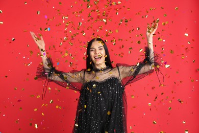 Emotional woman and falling confetti on red background