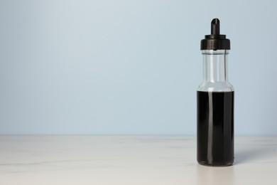 Photo of Bottle with soy sauce on white table, space for text