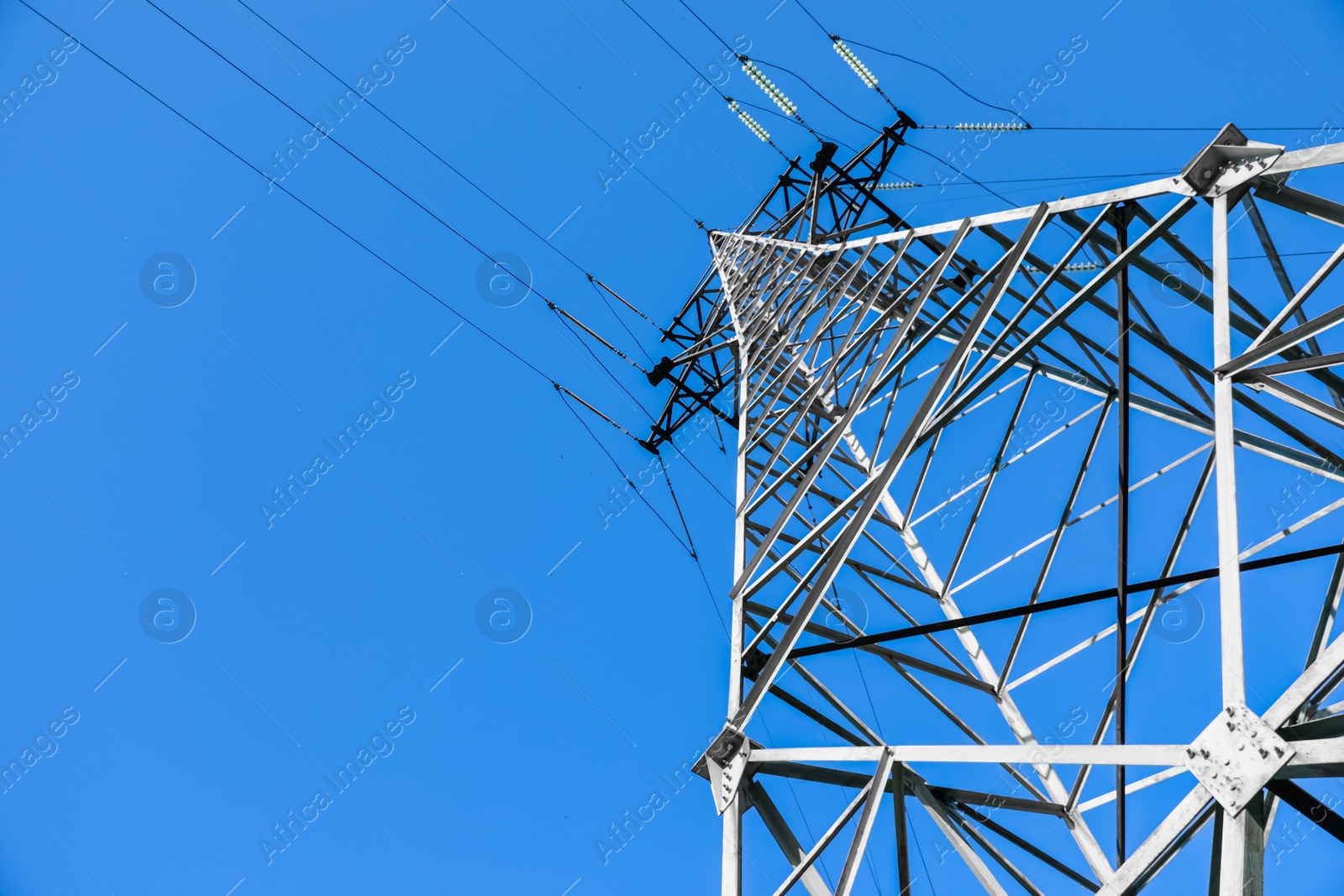 Photo of Modern high voltage tower against blue sky, low angle view