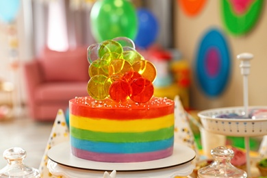 Bright birthday cake on table in decorated room