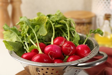 Wet radish in colander on white table, closeup