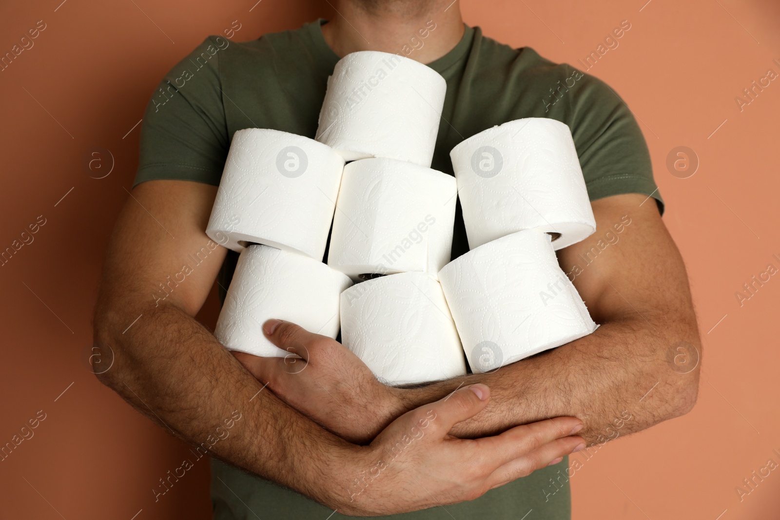 Photo of Man with heap of toilet paper rolls on brown background, closeup