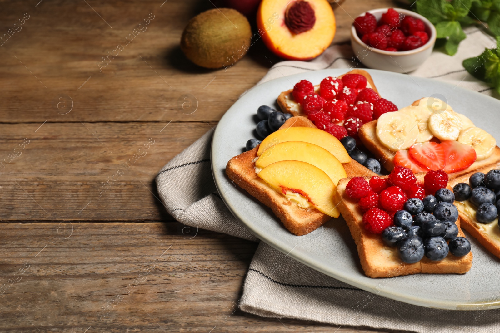 Photo of Tasty toasts with different spreads and fruits on wooden table. Space for text