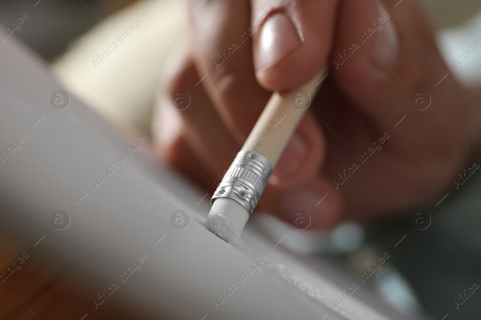 Photo of Man correcting picture on paper with pencil eraser, closeup