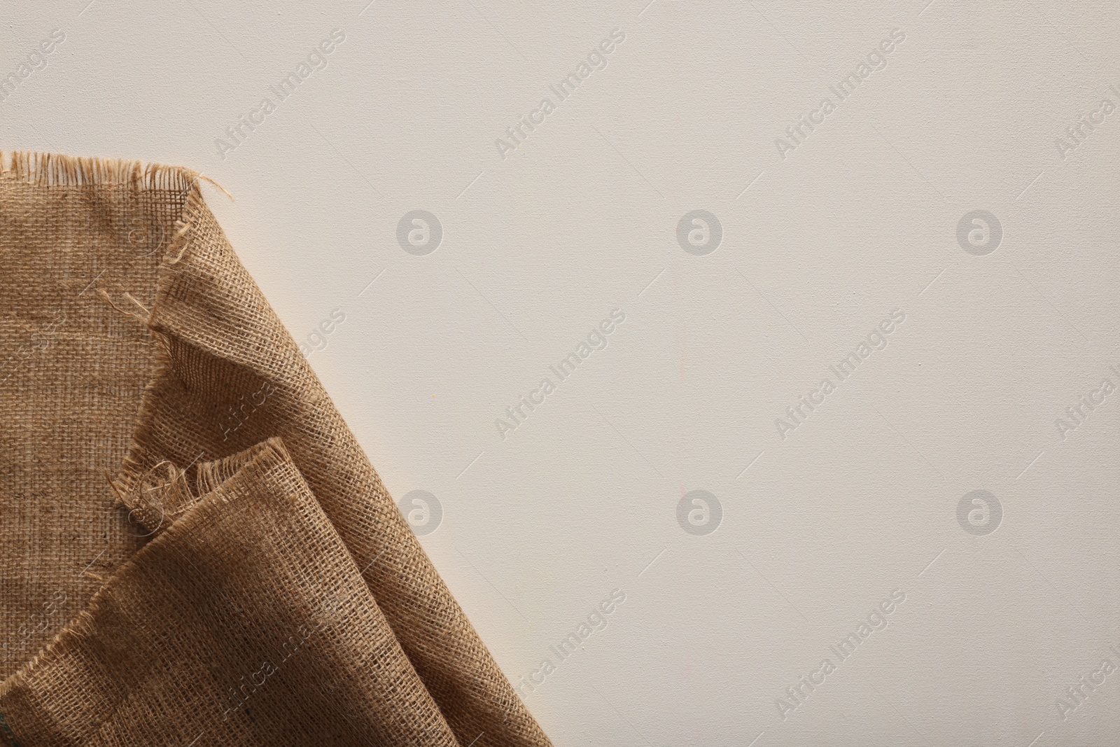 Photo of Natural burlap fabric on white background, top view. Space for text