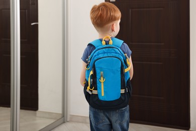 Little boy with backpack going to school, back view