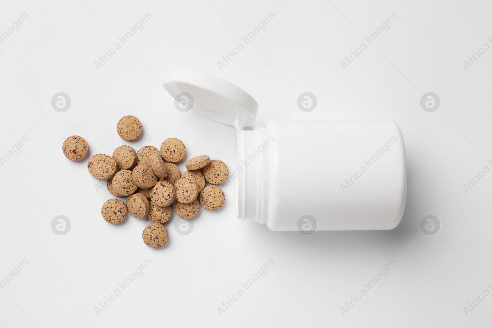 Photo of Vitamin pills and bottle on white background, top view