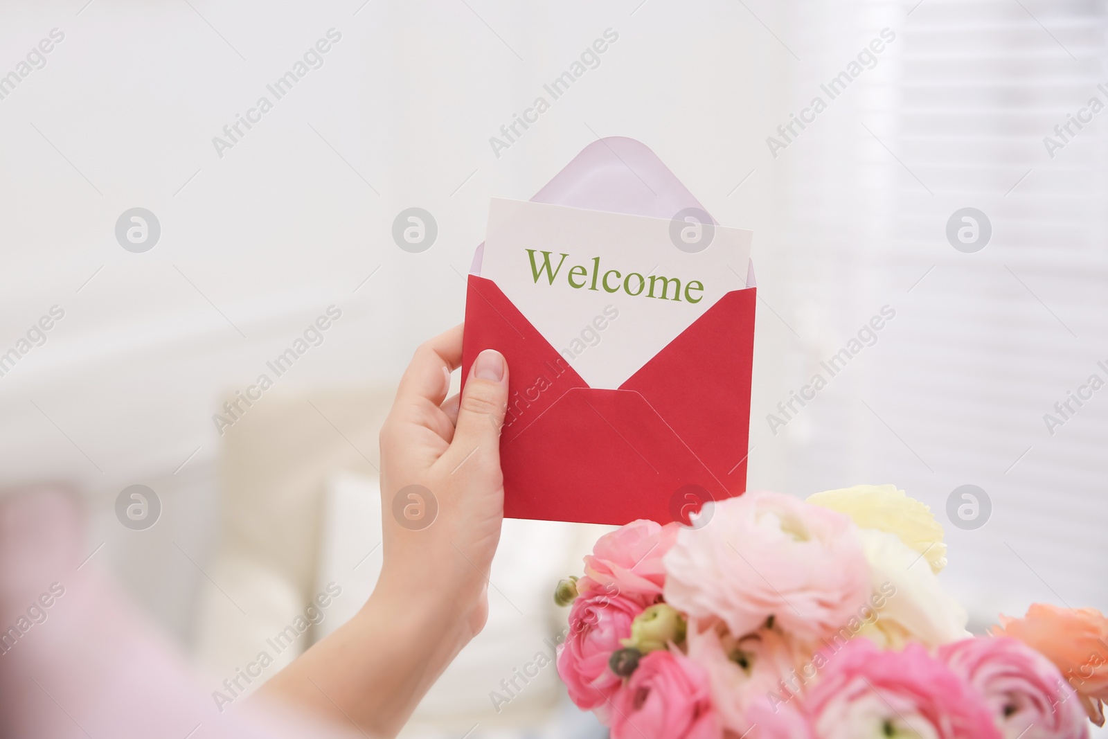 Image of Welcome card. Woman holding envelope and ranunculus flowers on indoors, closeup