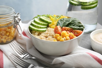 Photo of Healthy quinoa salad with vegetables in bowl served on table