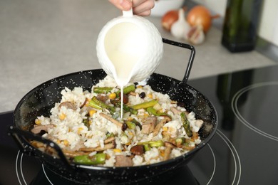 Photo of Woman cooking delicious risotto, closeup. Tasty recipe