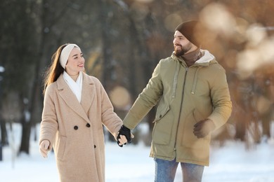 Beautiful happy couple walking in snowy park on winter day