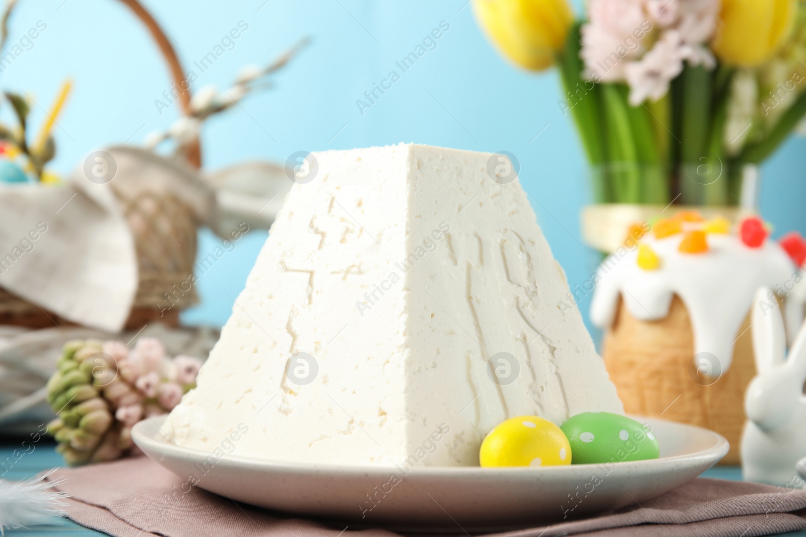 Photo of Traditional cottage cheese Easter paskha on light blue table, closeup