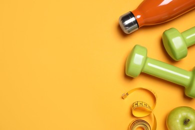 Photo of Dumbbells, bottle, apple and measuring tape on orange background, flat lay. Space for text