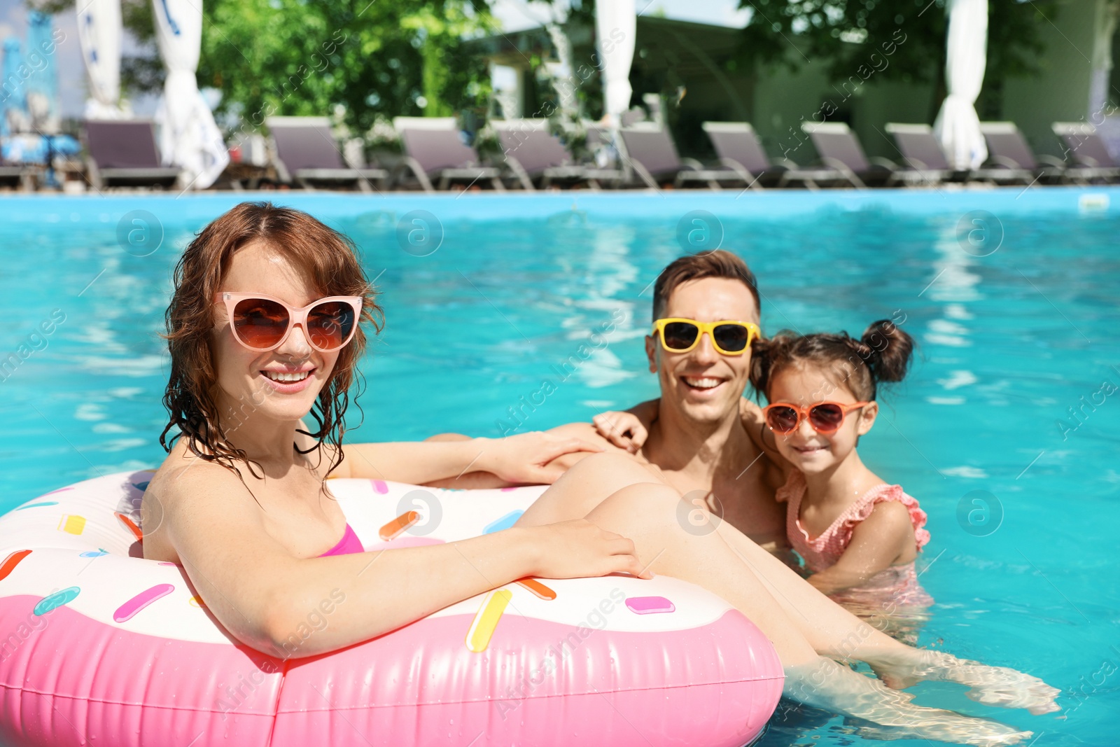 Photo of Happy family in swimming pool at resort