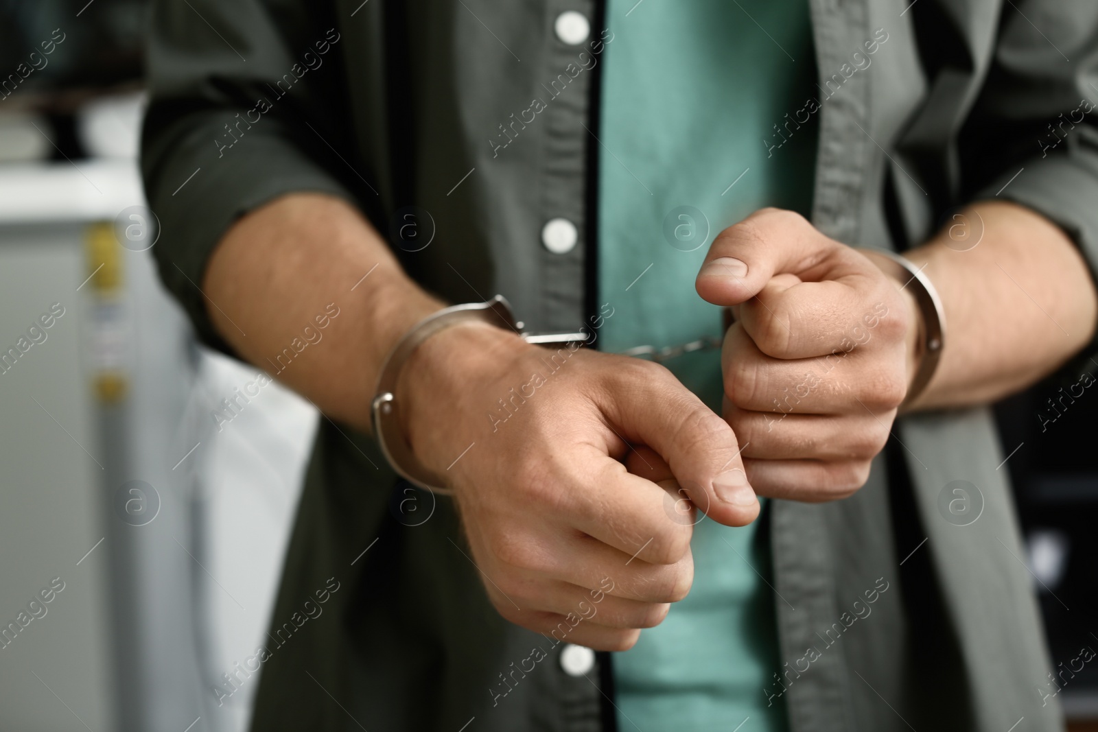 Photo of Man detained in handcuffs indoors, closeup view. Criminal law