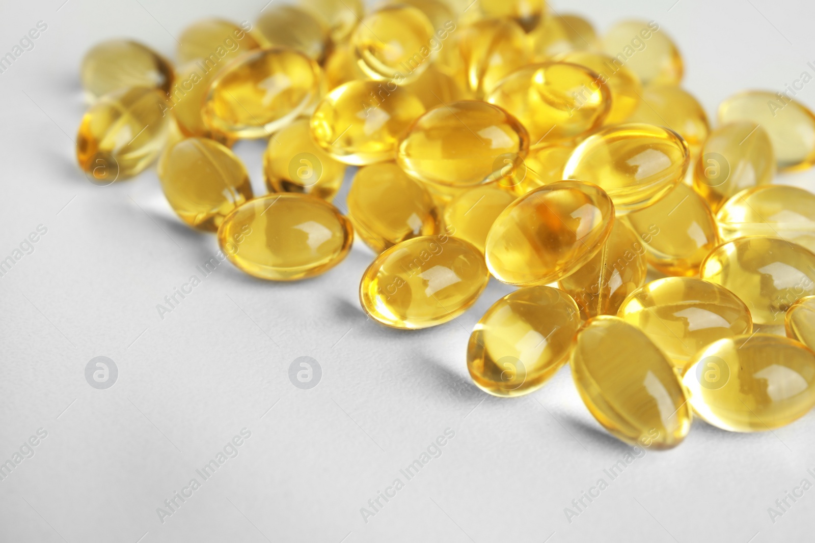Photo of Cod liver oil pills on light background, closeup