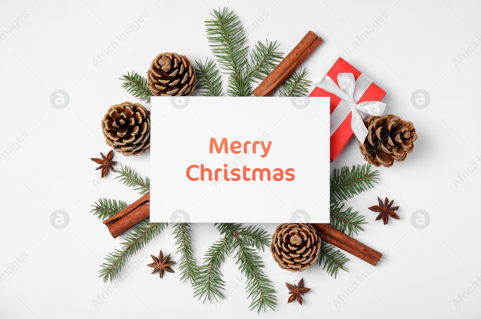 Image of Greeting card with phrase Merry Christmas, beautiful fir tree branches, gift box, pine cones and cinnamon sticks on white background, flat lay