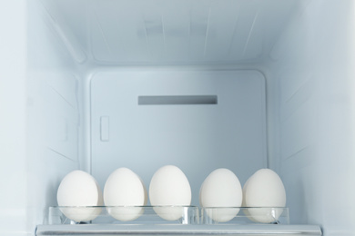 Photo of Fresh eggs on shelf in modern refrigerator