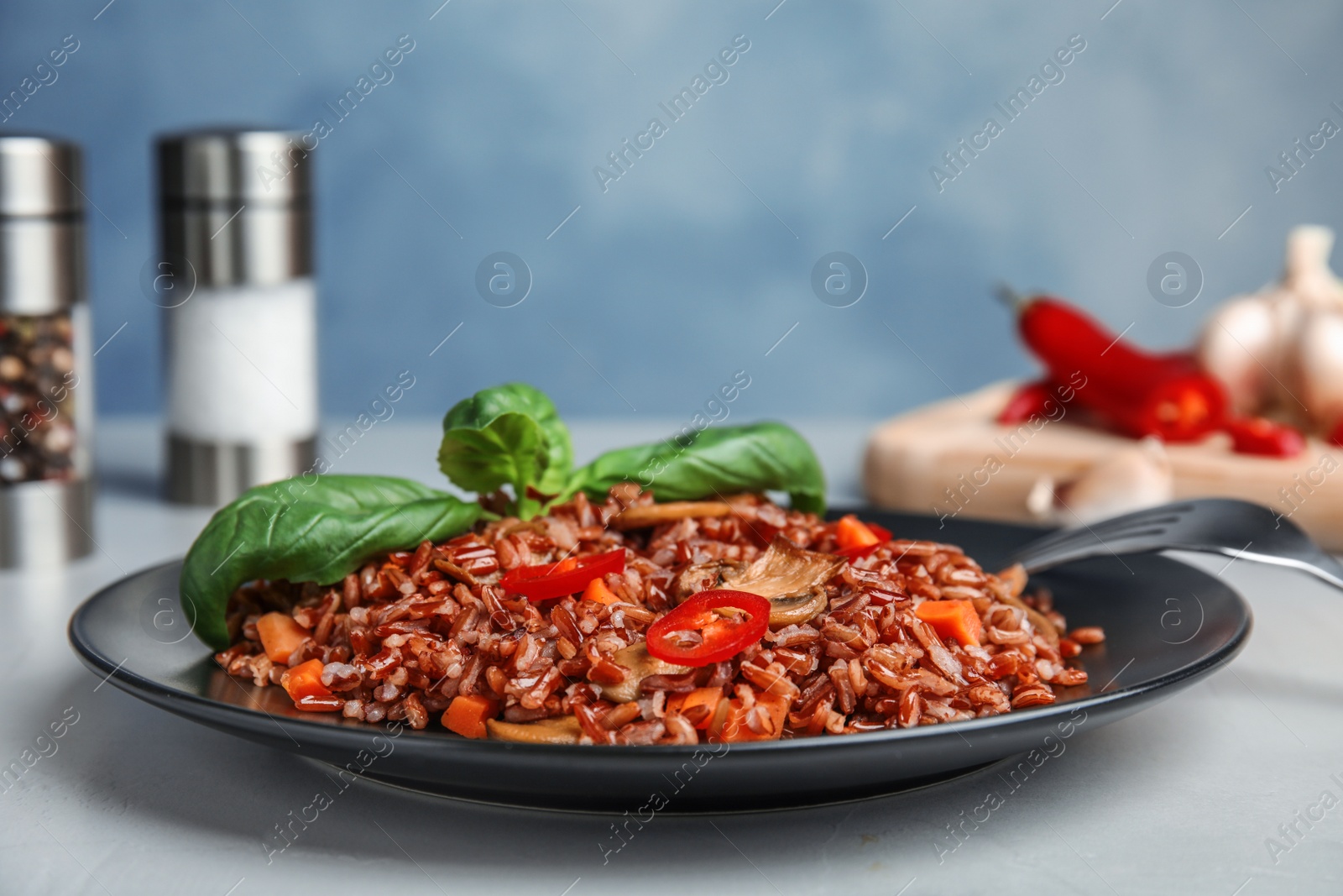 Photo of Plate of brown rice with vegetables on table, closeup. Space for text