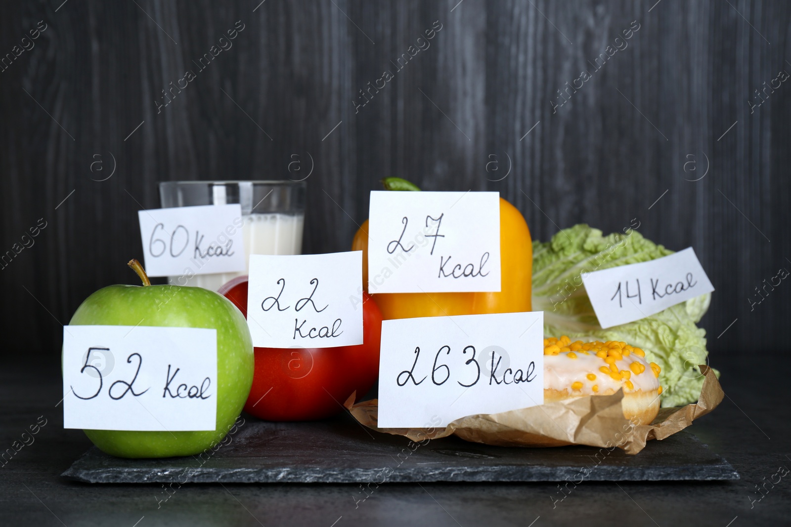 Photo of Food products with calorific value tags on black table. Weight loss concept