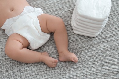 Photo of Cute little baby in diaper on grey blanket, above view
