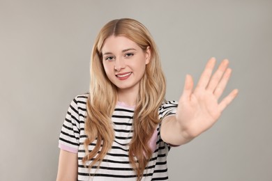 Photo of Happy woman giving high five on light grey background