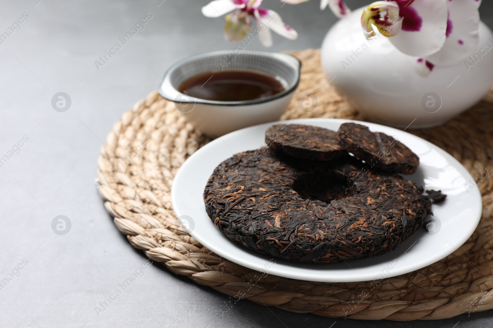 Photo of Plate with disc shaped pu-erh tea on light grey table, closeup