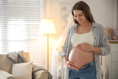 Happy pregnant woman touching her belly indoors