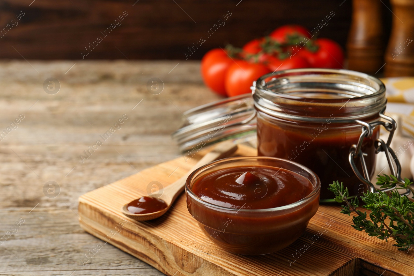 Photo of Tasty barbeque sauce in bowl, jar and spoon on wooden table, closeup. Space for text