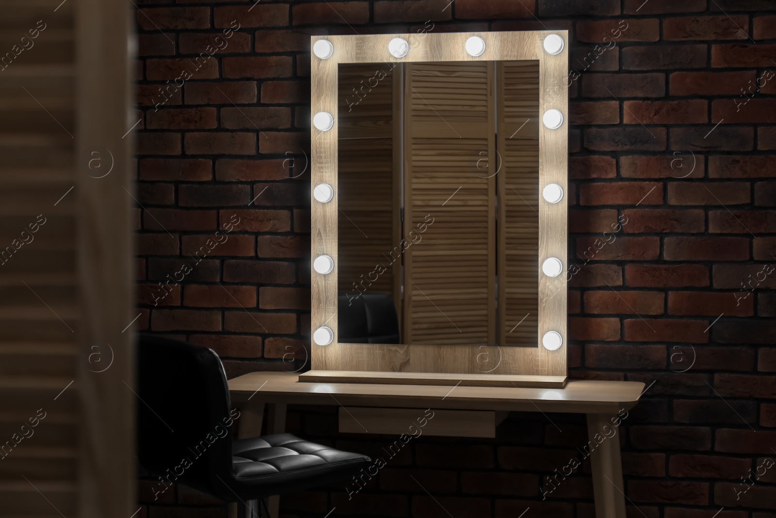 Photo of Mirror with light bulbs, table and chair in makeup room