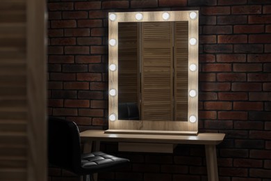 Photo of Mirror with light bulbs, table and chair in makeup room