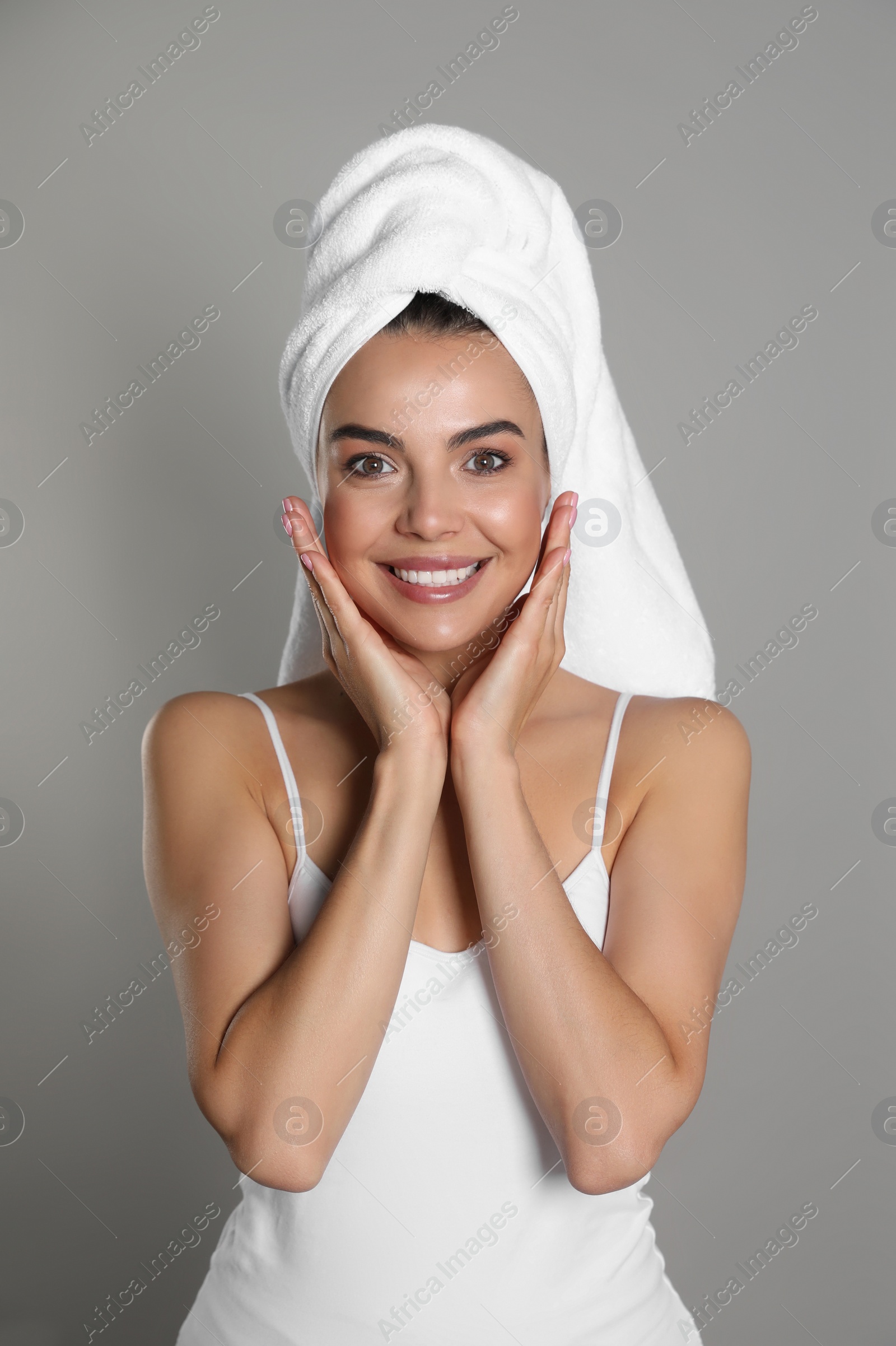 Photo of Beautiful young woman with towel on head against grey background