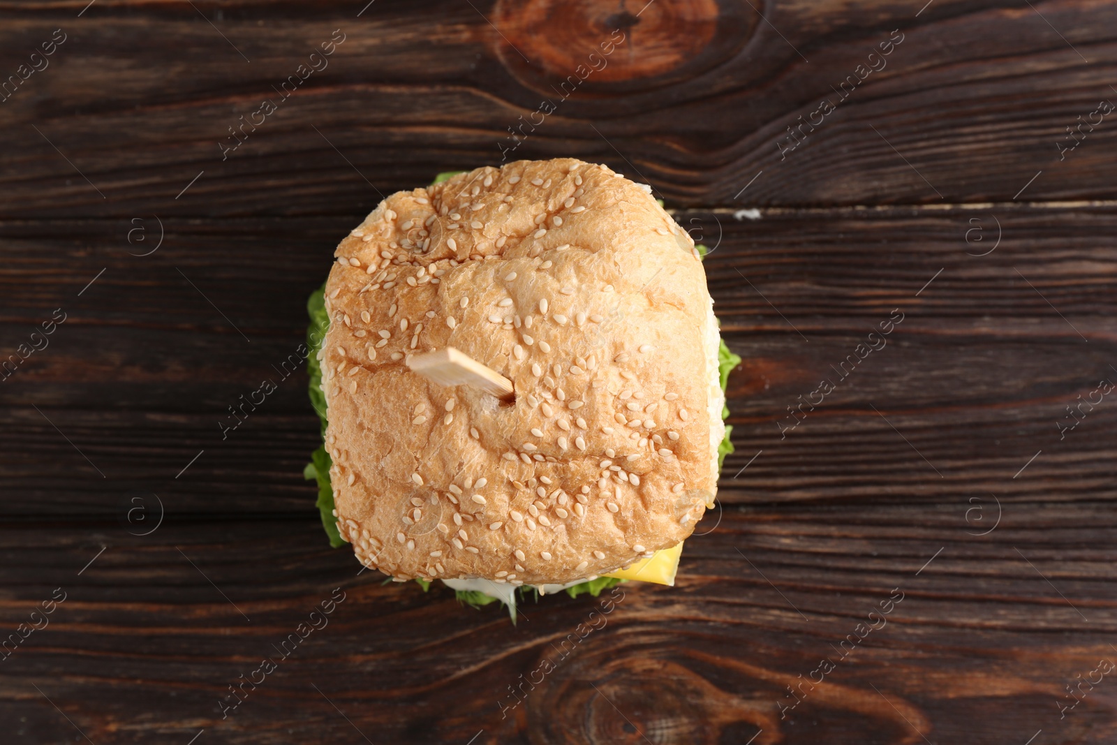 Photo of Delicious vegetarian burger on wooden table, top view