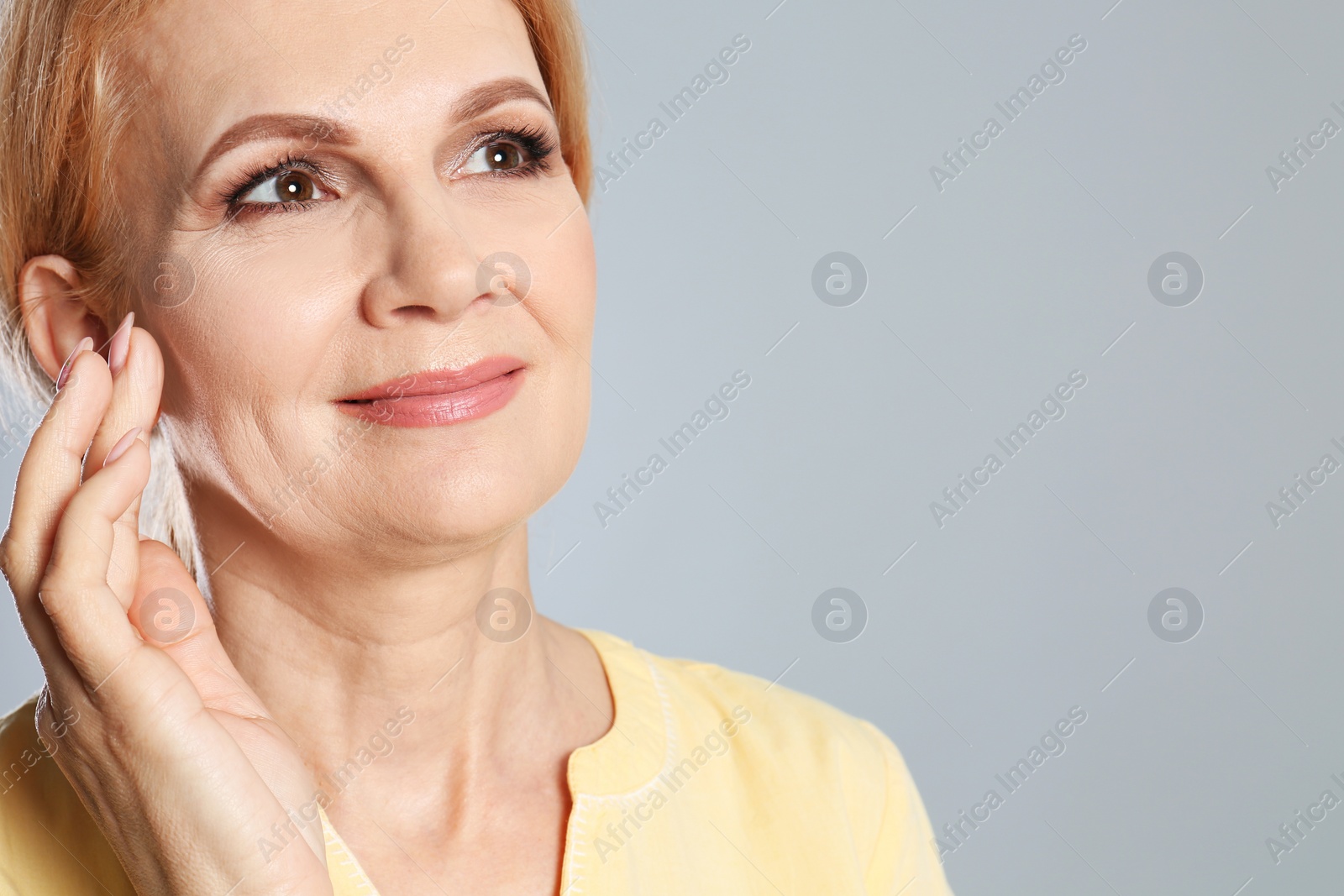 Photo of Portrait of mature woman with beautiful face on grey background. Space for text