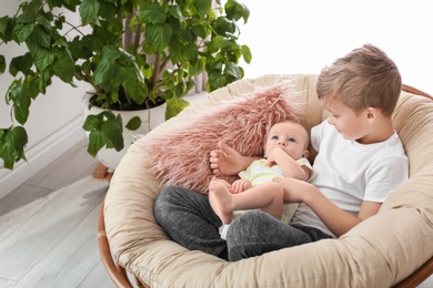 Photo of Cute boy with little baby in lounge chair at home