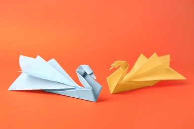 Photo of Origami art. Beautiful paper swans on orange background
