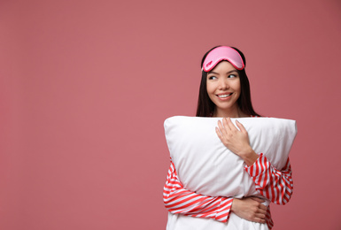 Photo of Beautiful Asian woman with pillow on dusty rose background, space for text. Bedtime